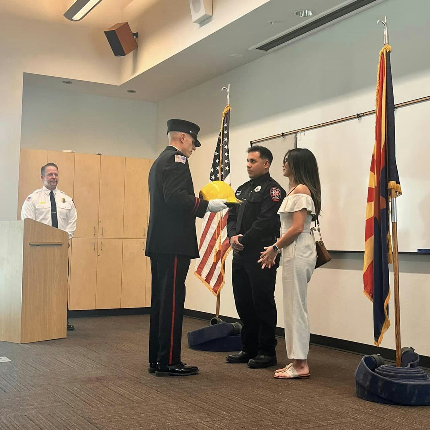 A ceremony with a person in uniform presenting a folded American flag to others, likely a military or public service event.