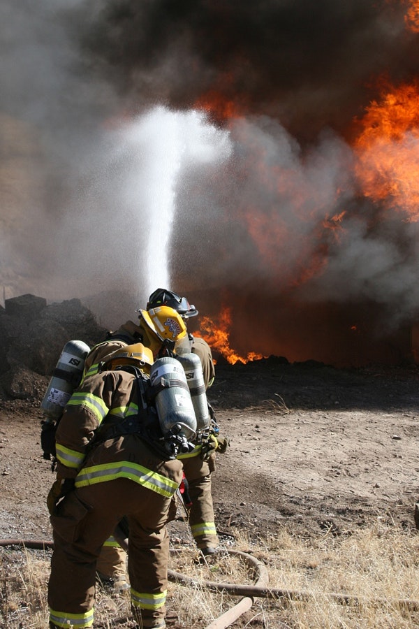 Firefighters battling a blaze, spraying water on flames.