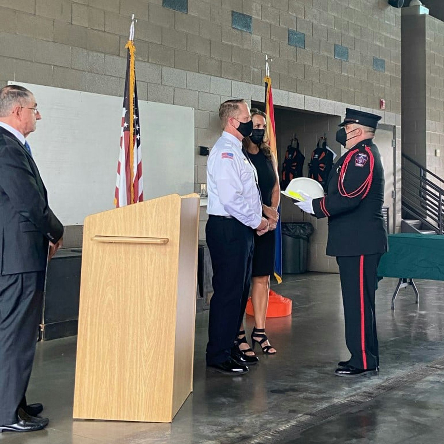 A ceremony with uniformed individuals, one holding a helmet, American flags, and a podium.