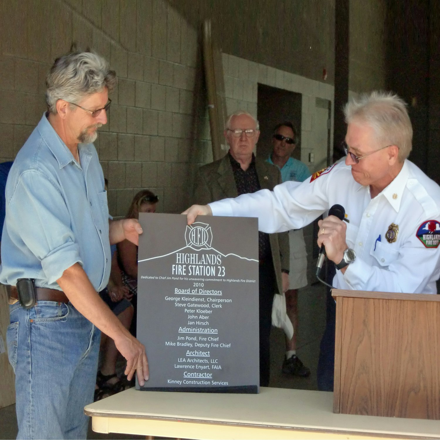 Two men unveiling a plaque for Highlands Fire Station 23 at a ceremony.
