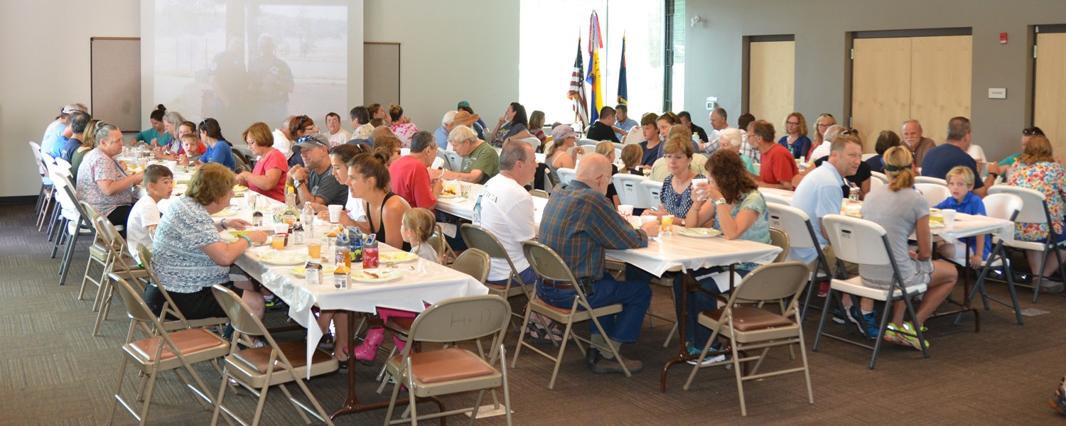 A large group of people dining at long tables in a spacious, well-lit room.