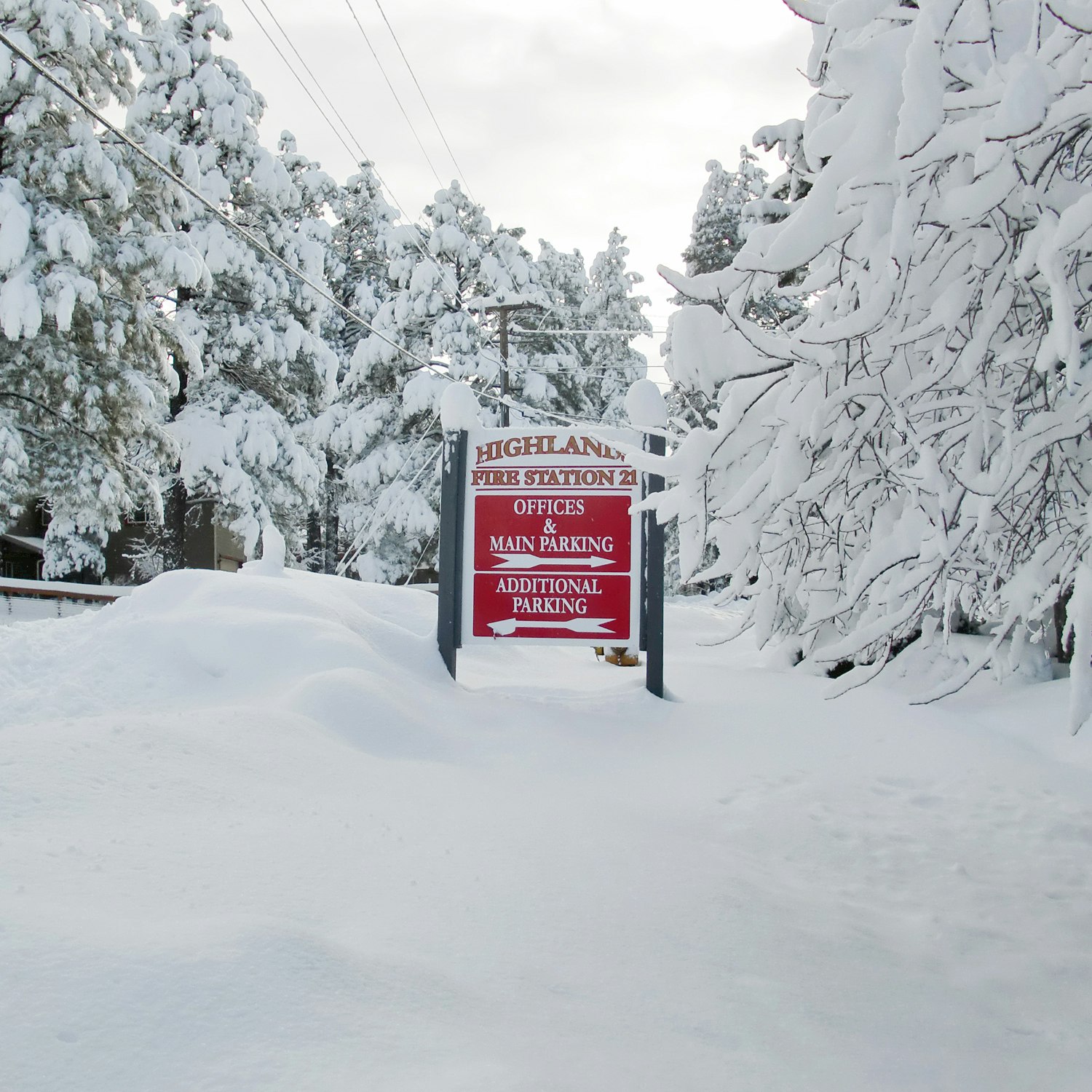 Snow-covered landscape with a sign for Highland Fire Station 21 and directions for parking.