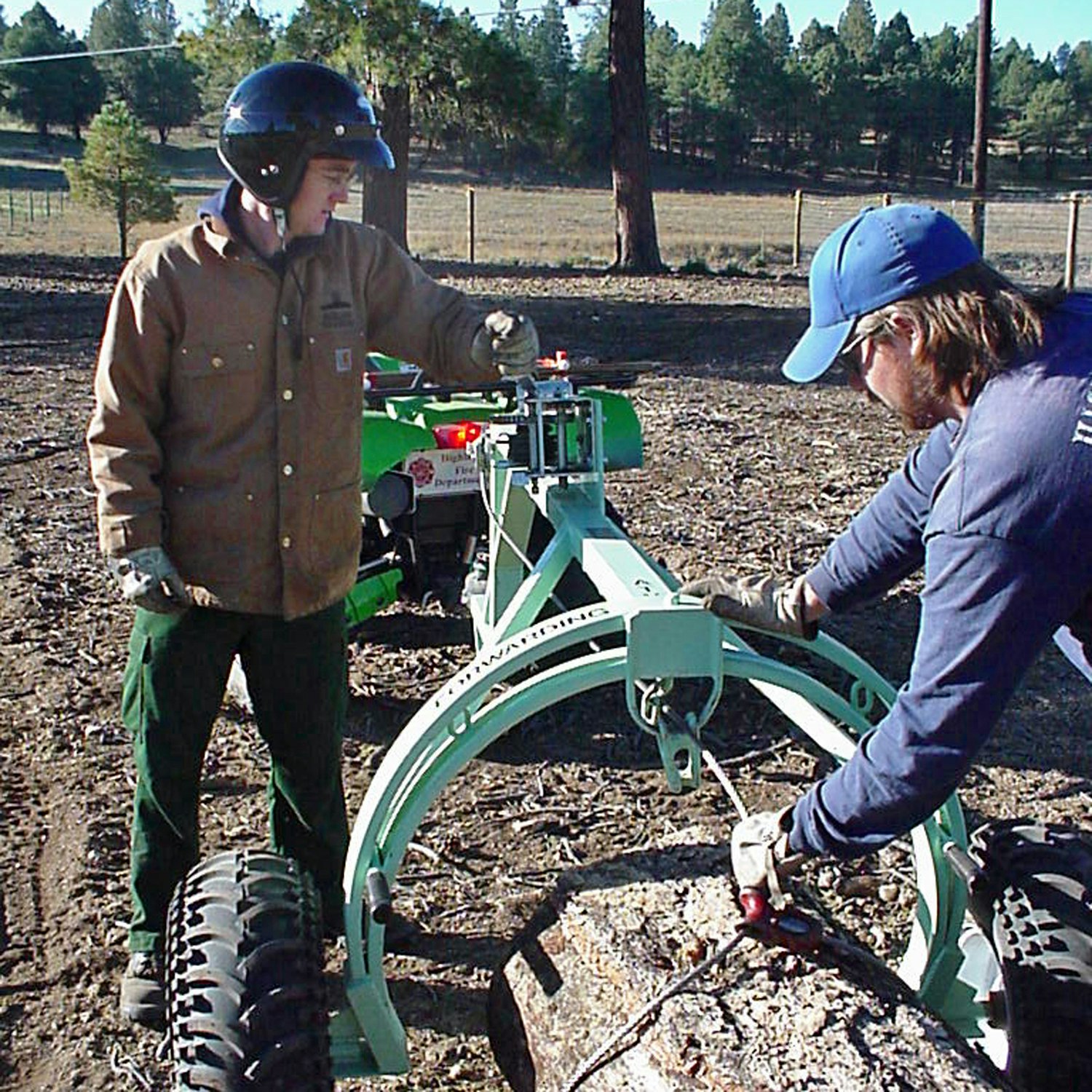Two people with a log-splitting machine outdoors.