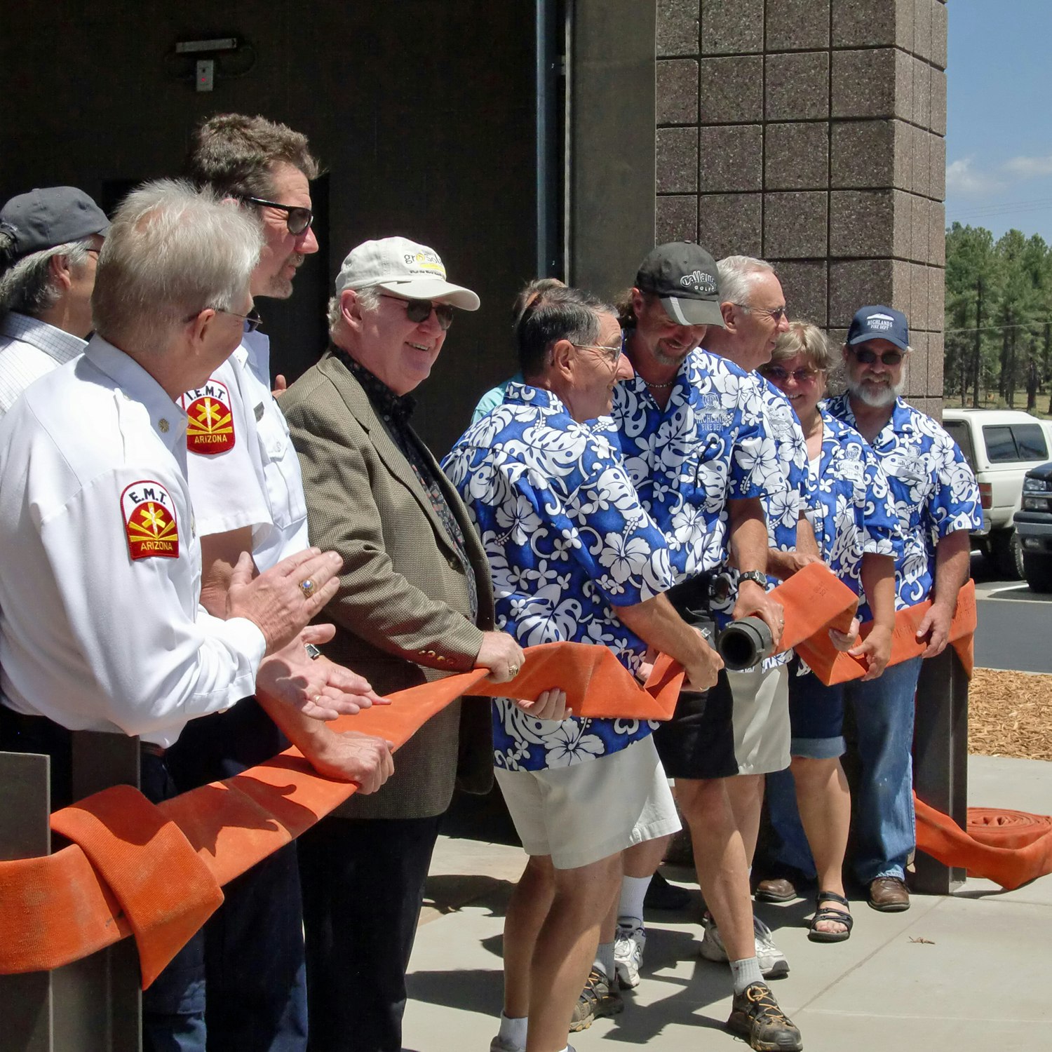 Group of people in matching blue shirts at a ribbon-cutting ceremony.