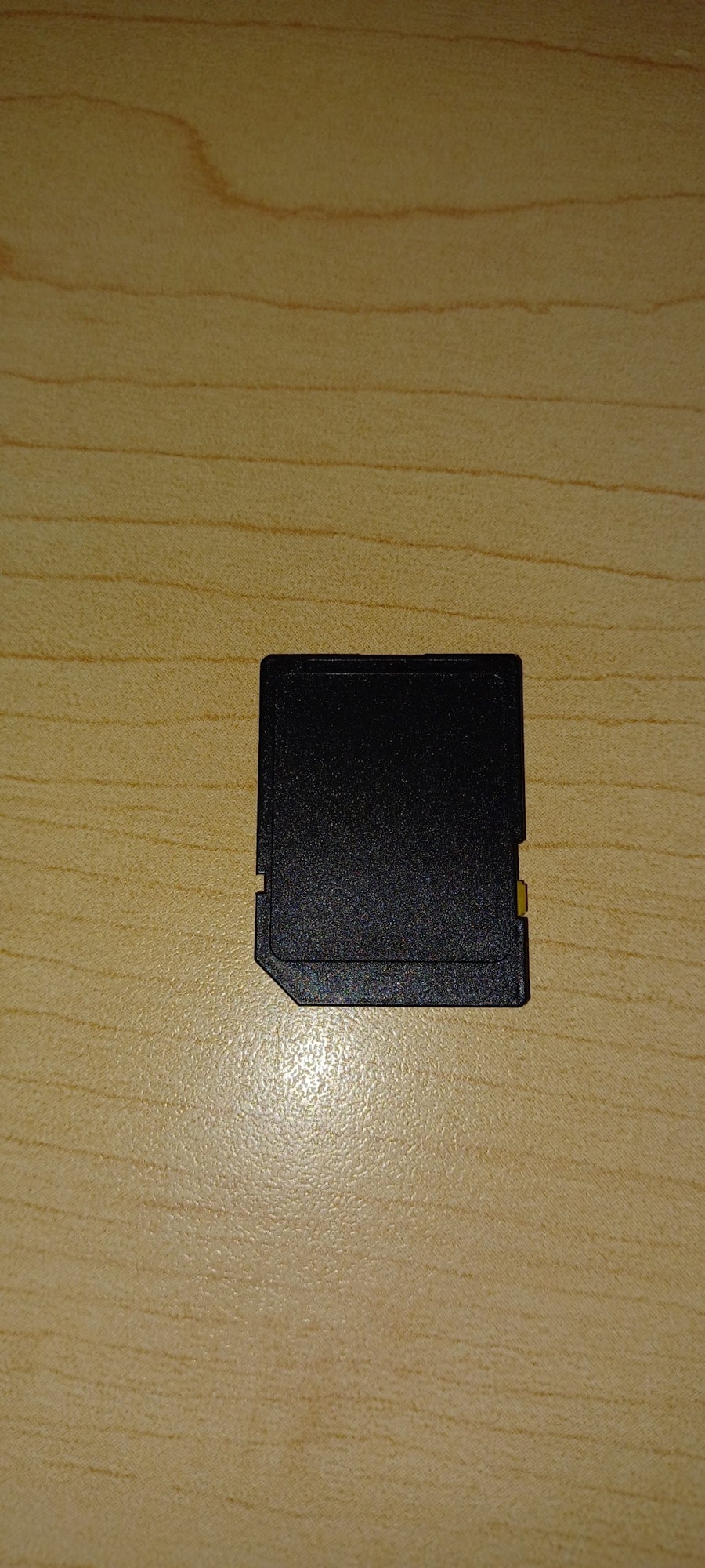 A black SD card on a wooden surface.