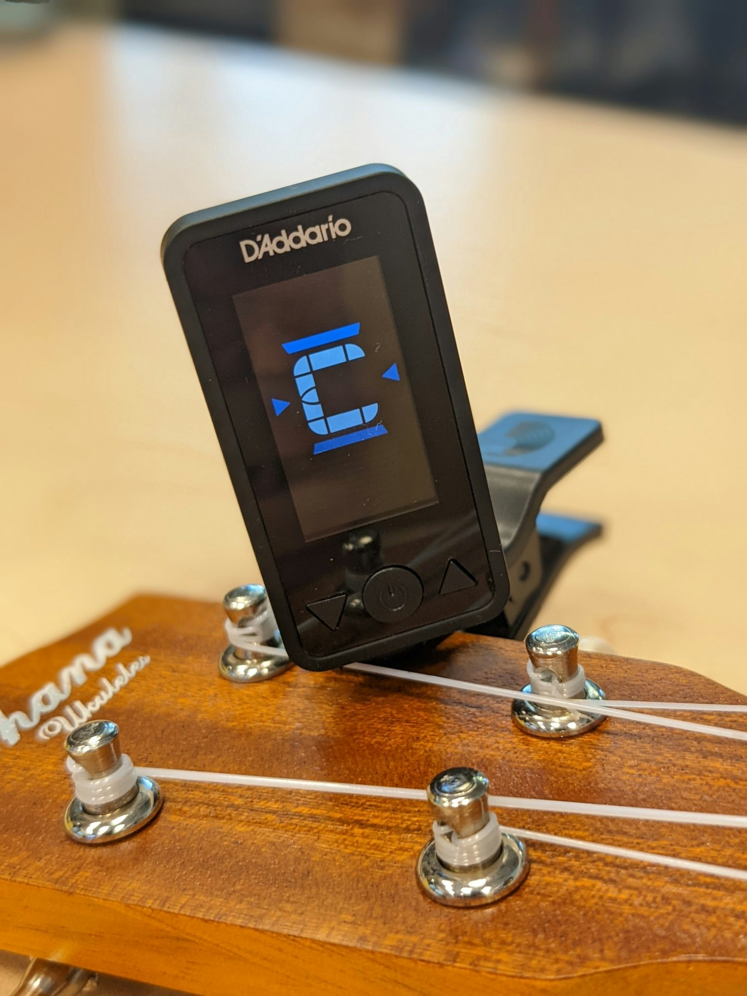 A D'Addario tuner clipped onto a ukulele headstock, showing the note "C".