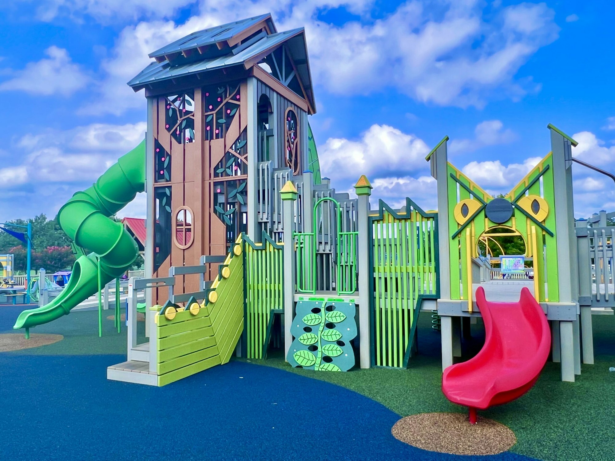 A colorful playground featuring a large structure with slides, steps, and playful designs, set against a bright blue sky.