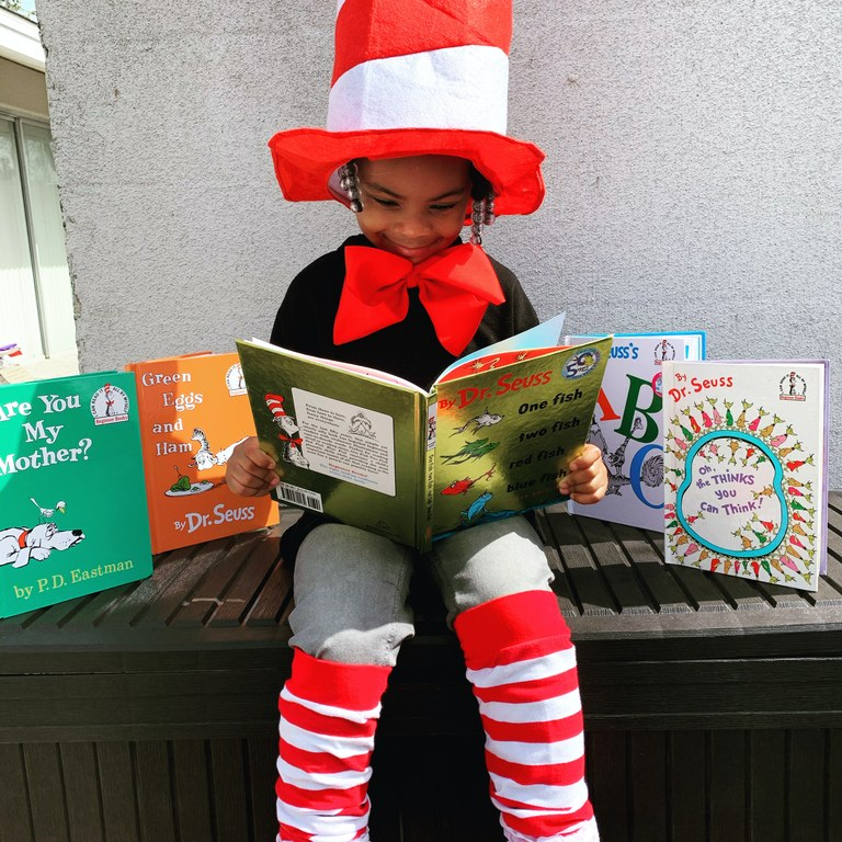 Photo of a child dressed as the Cat in the Hat and reading a book
