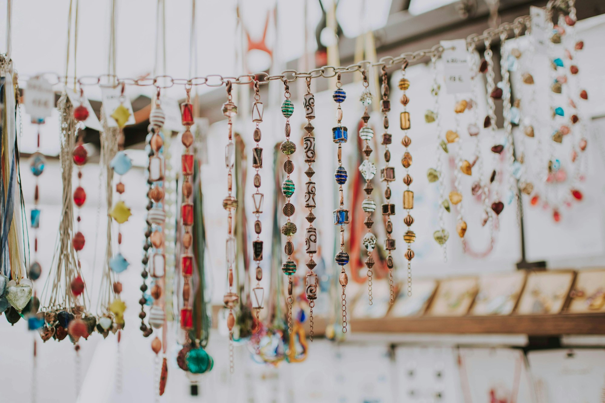 Colorful necklaces with various beads and pendants hanging in a display.