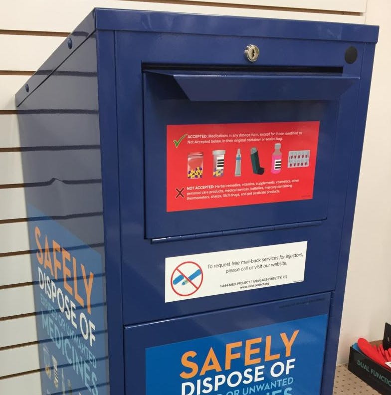 A blue medicine disposal box with guidelines for accepting and rejecting items for safe disposal of expired medications.