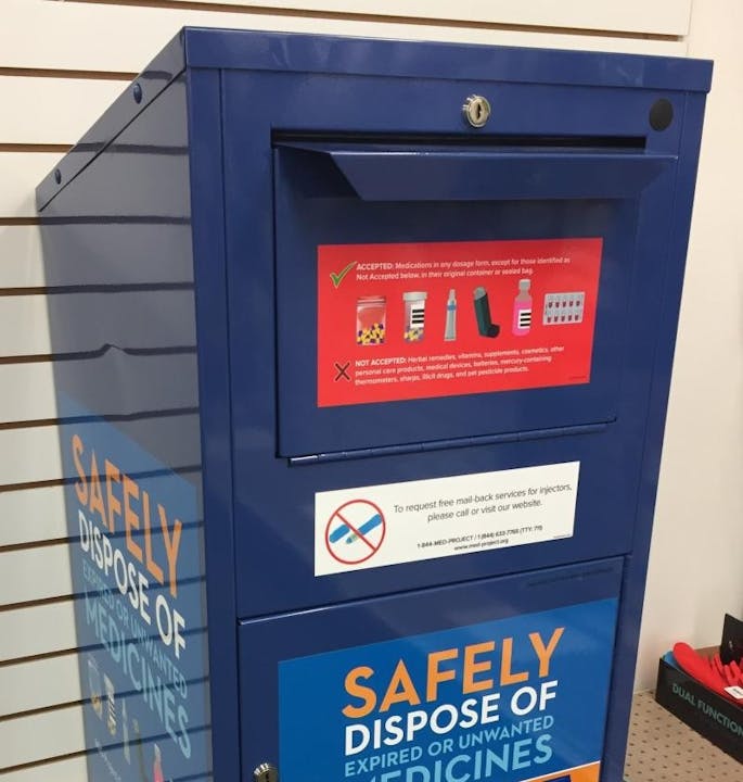 A blue medicine disposal box with instructions on accepted and not accepted items for safe disposal.