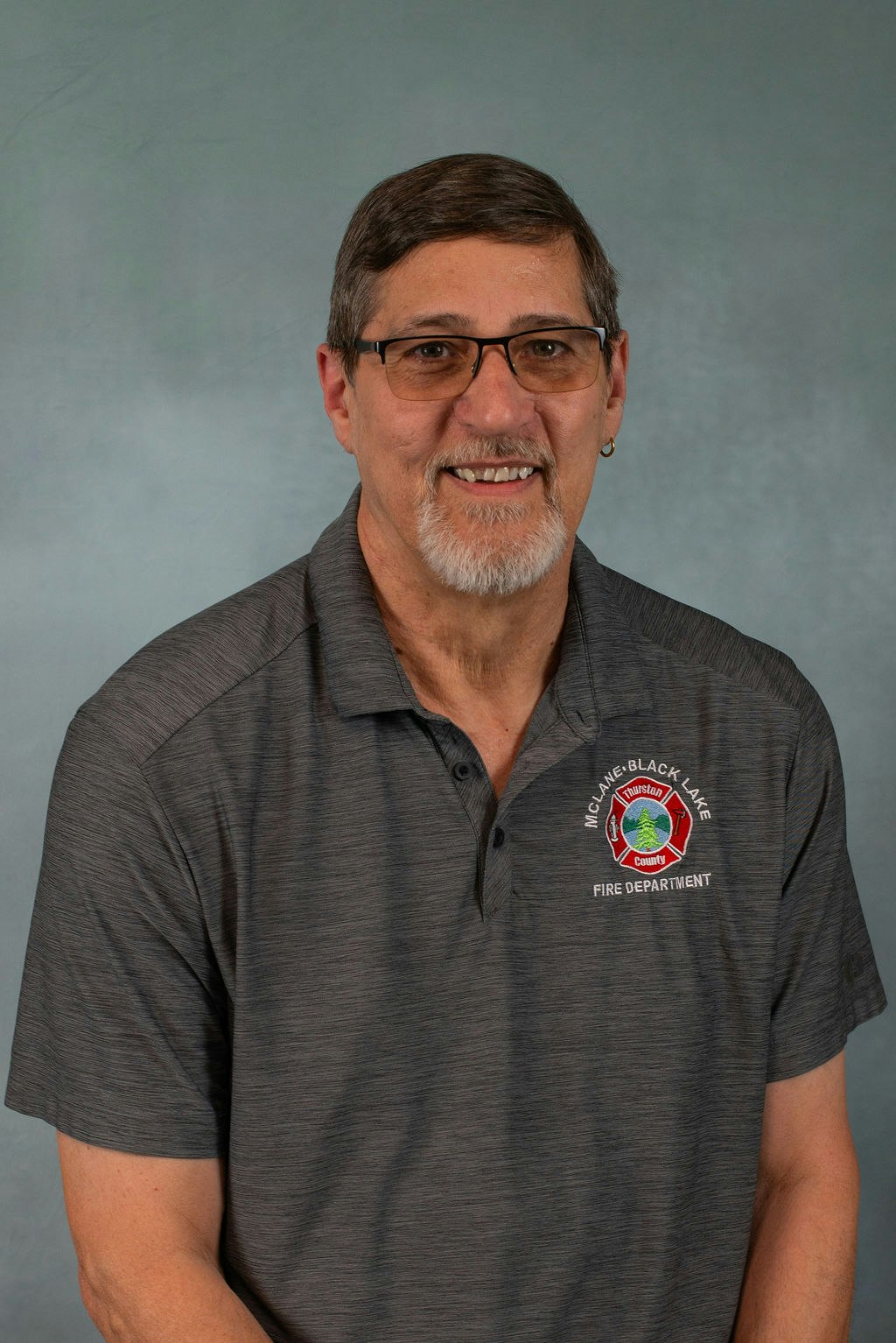 Person in a gray "McLane-Black Lake Fire Department" polo shirt, smiling.