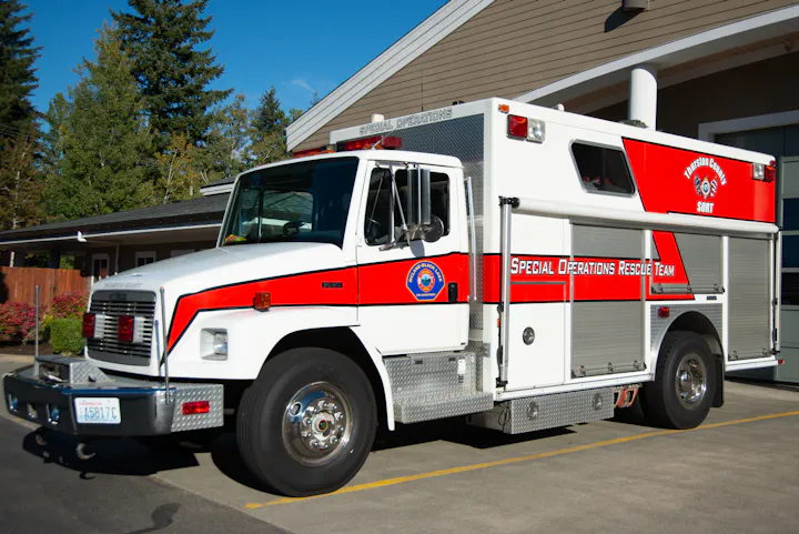 A specialized rescue vehicle from the Special Operations Rescue Team, parked outside a building among trees.