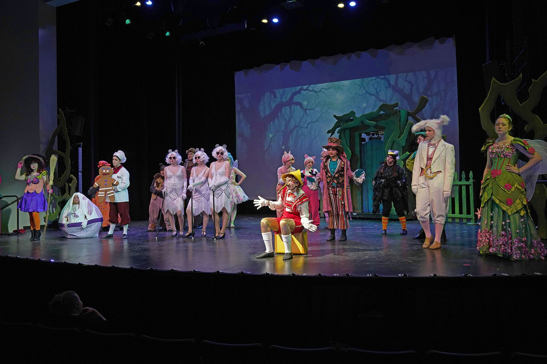 A theater performance with actors in colorful, whimsical costumes on stage.