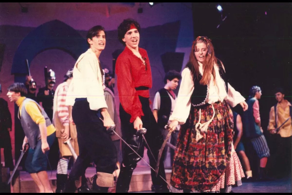A group of people in costume performing on stage with swords.