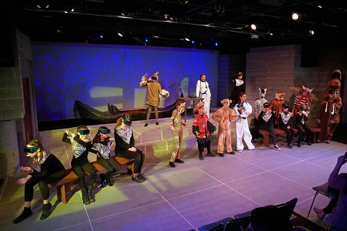 A group of people in animal and unique costumes performing on a stage with colorful lighting effects.