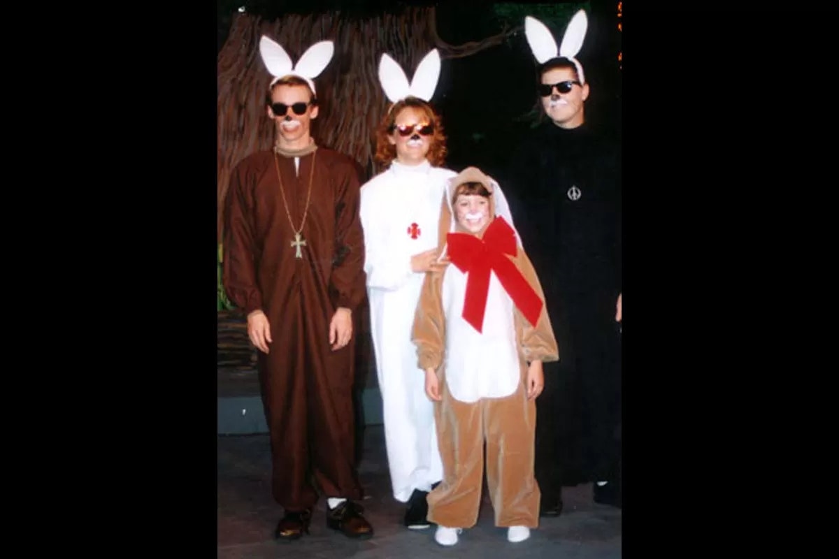 Four people in animal costumes with bunny ears, wearing sunglasses, posing for a group photo.