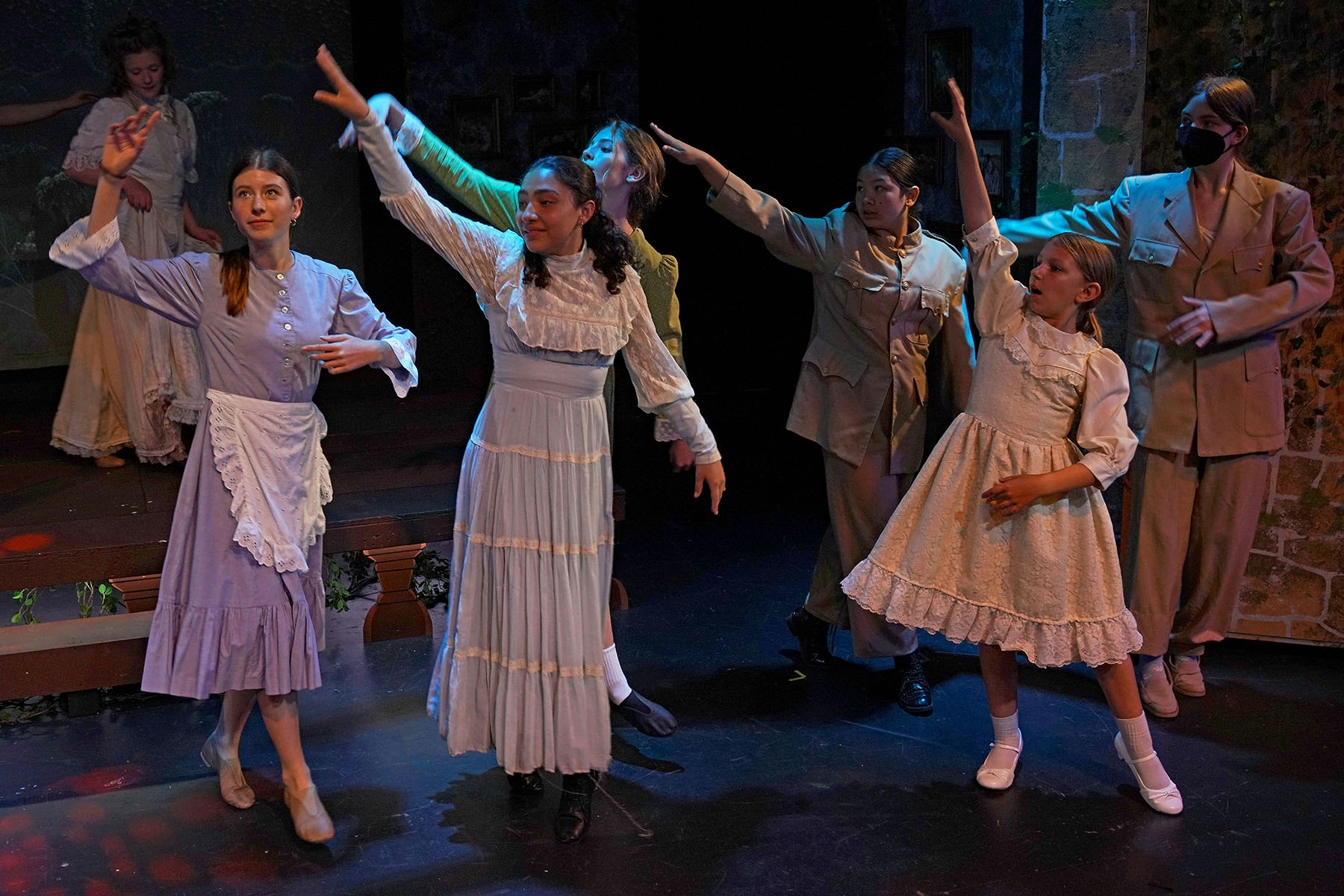 A theatrical performance with people in vintage costumes and military attire, gesturing on stage.