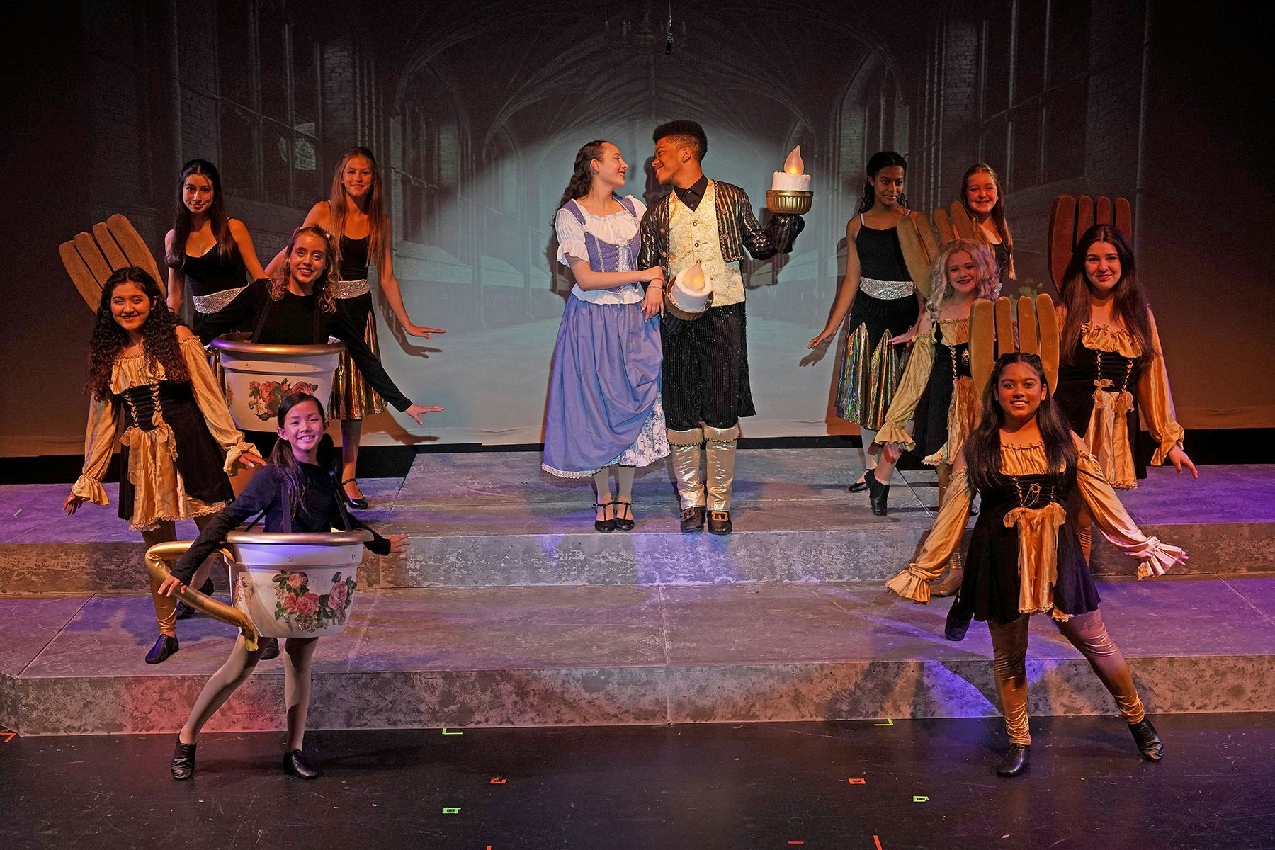 A theatrical performance with actors in costume, including a girl in blue and a boy holding a candle-like prop.