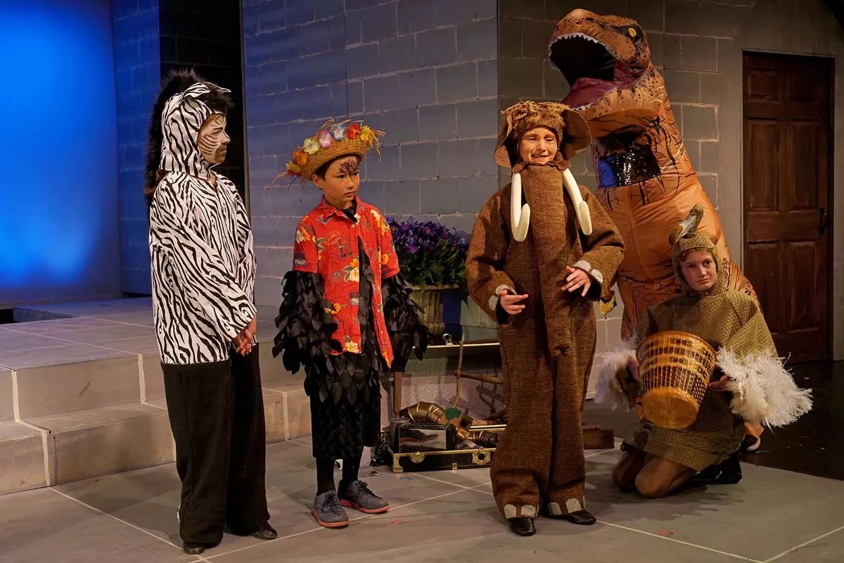 Children dressed in various animal and themed costumes on a stage.
