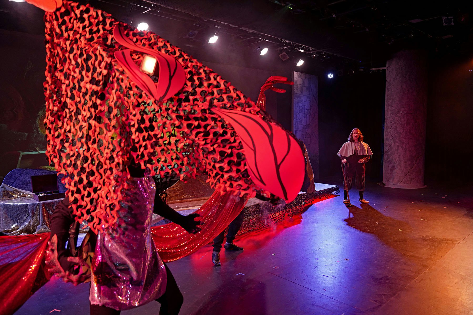 A theatrical performance with colorful costumes, dramatic lighting, and an abstract set design.