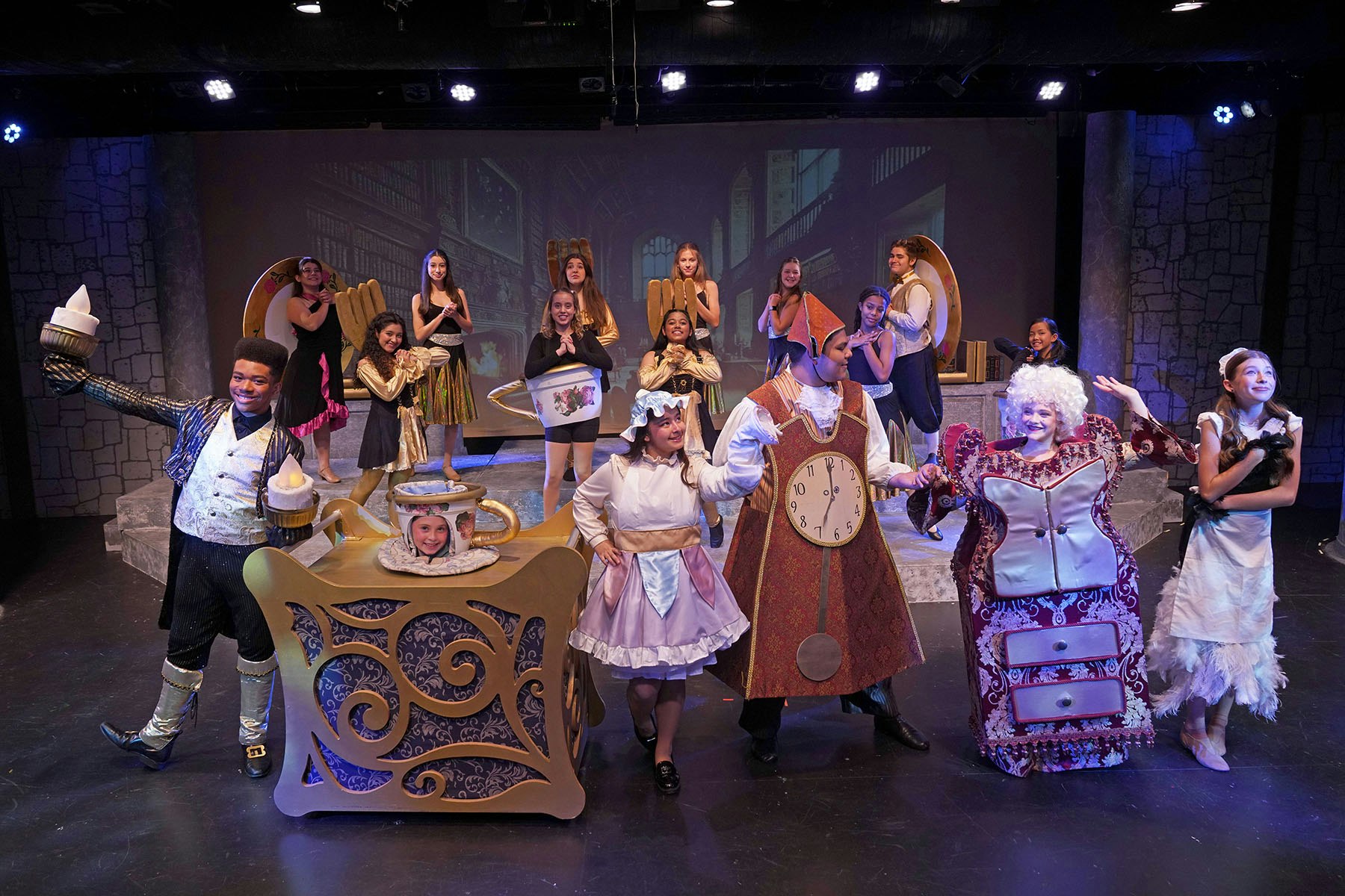 People in theatrical costumes performing "Beauty and the Beast" on stage.