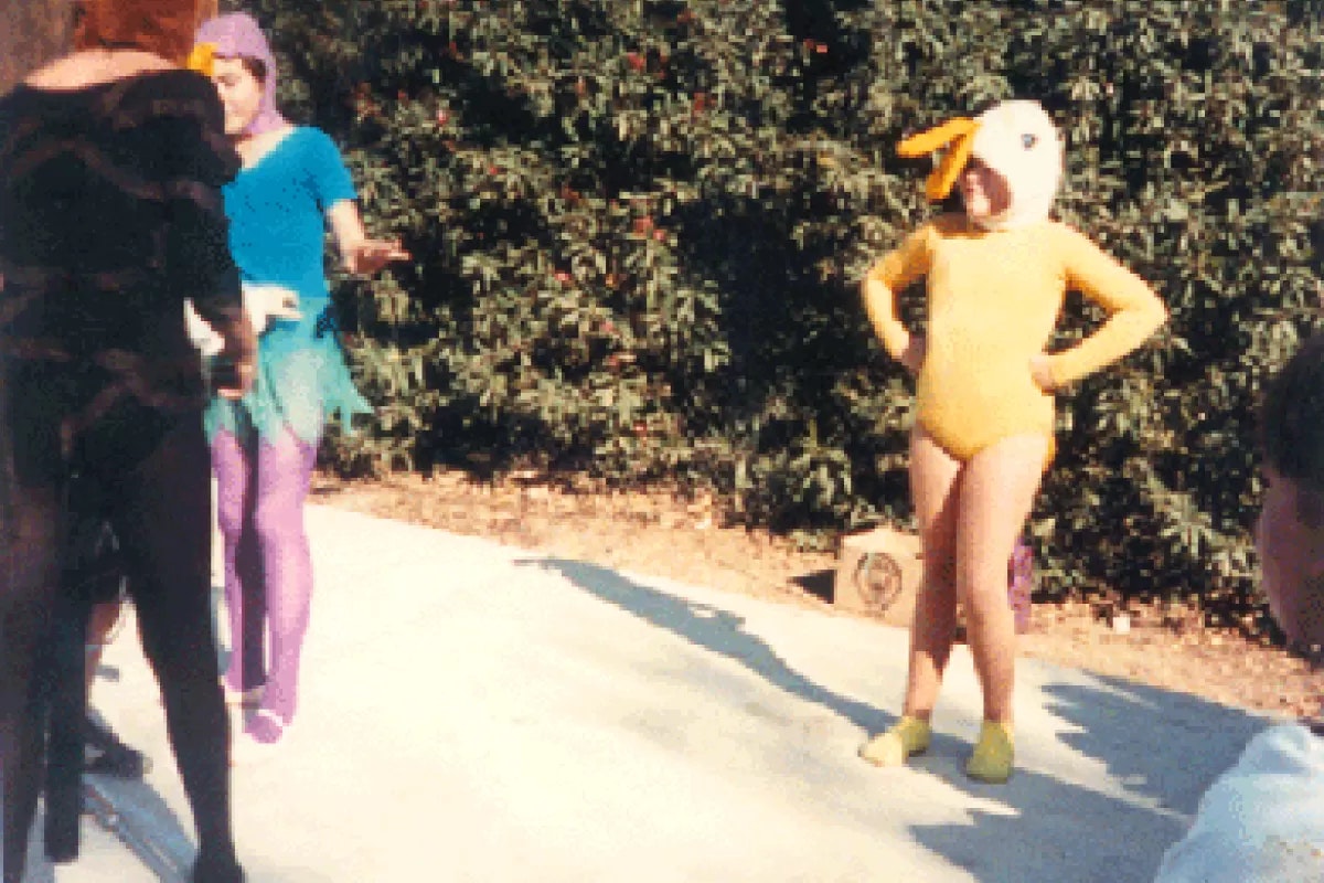 People in colorful costumes outdoors, with one in a yellow outfit resembling a duck.