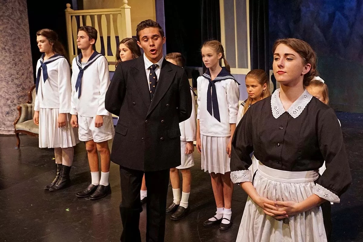 A group of people in costumes, possibly in a stage play, including a person in a maid outfit and others in sailor-style uniforms.
