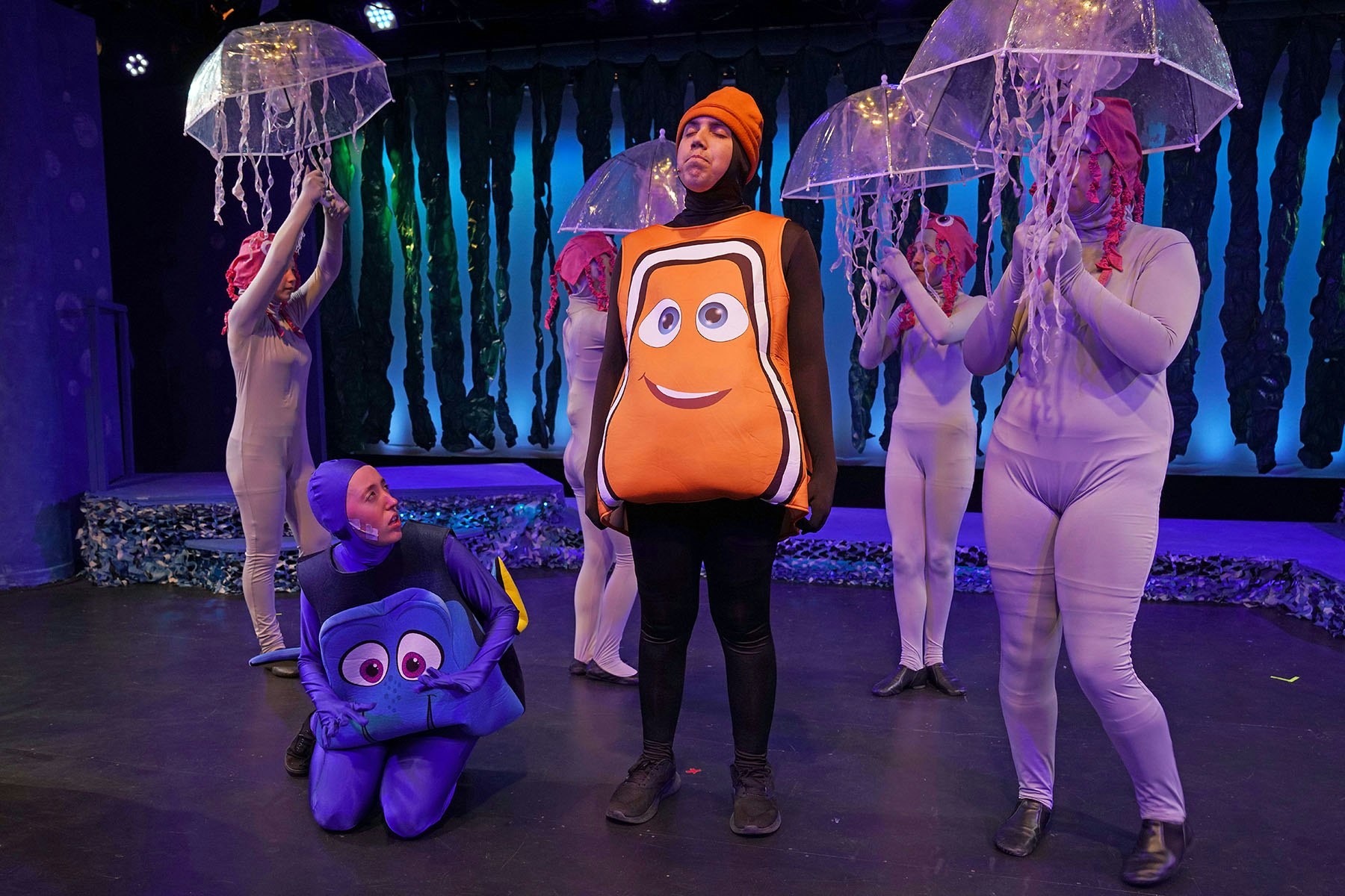 People in sea-themed costumes on stage, with jellyfish and fish outfits.