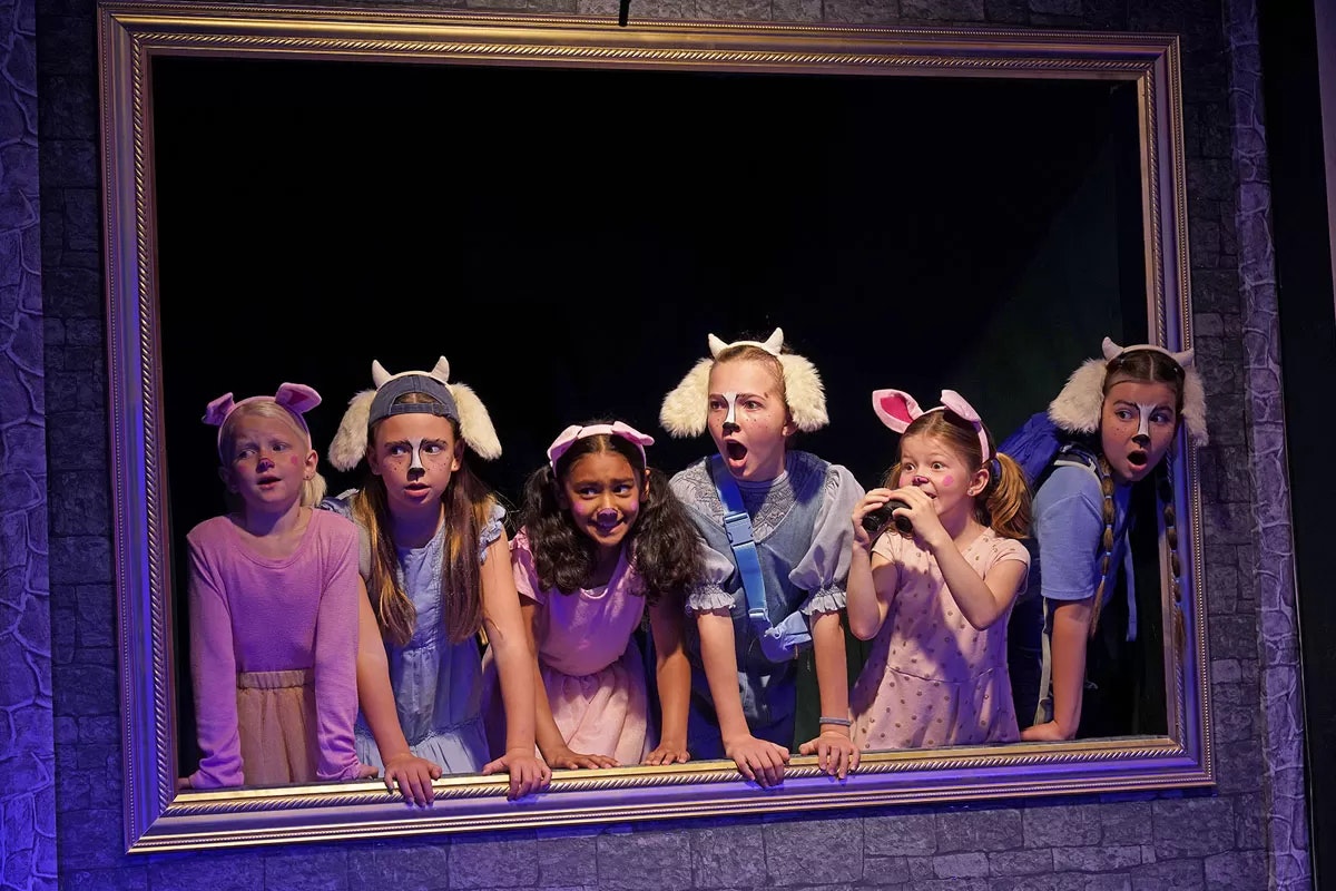 Children in animal costumes, looking surprised, framed as if in a painting.