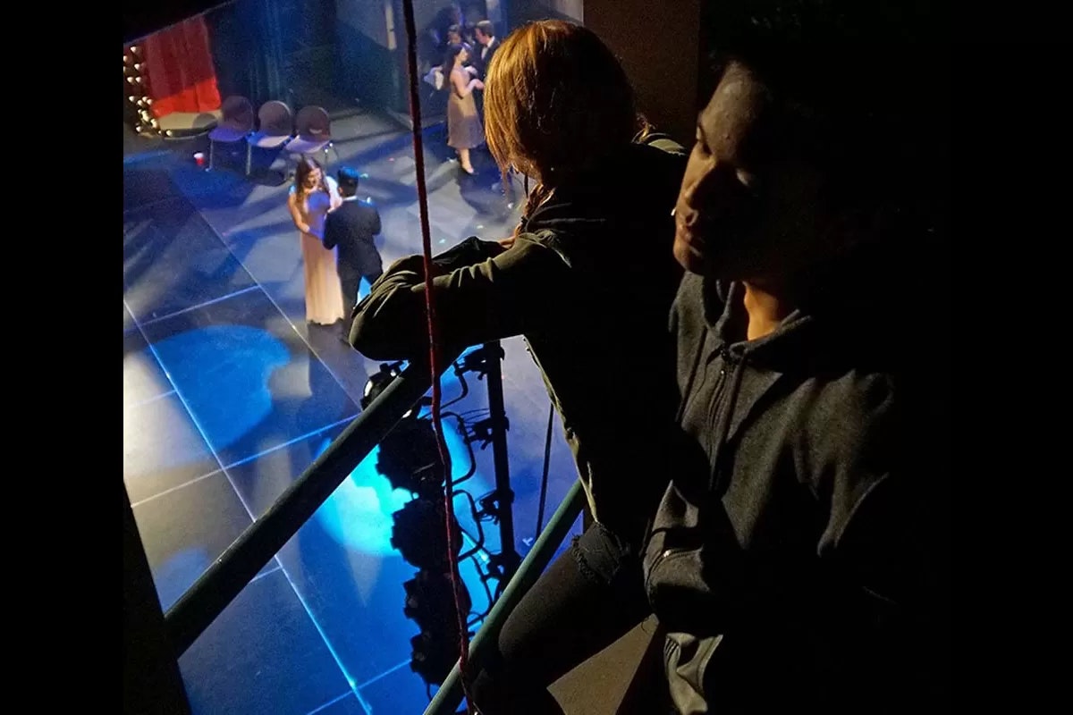 People are watching a stage performance from above, with dancers in elegant attire.