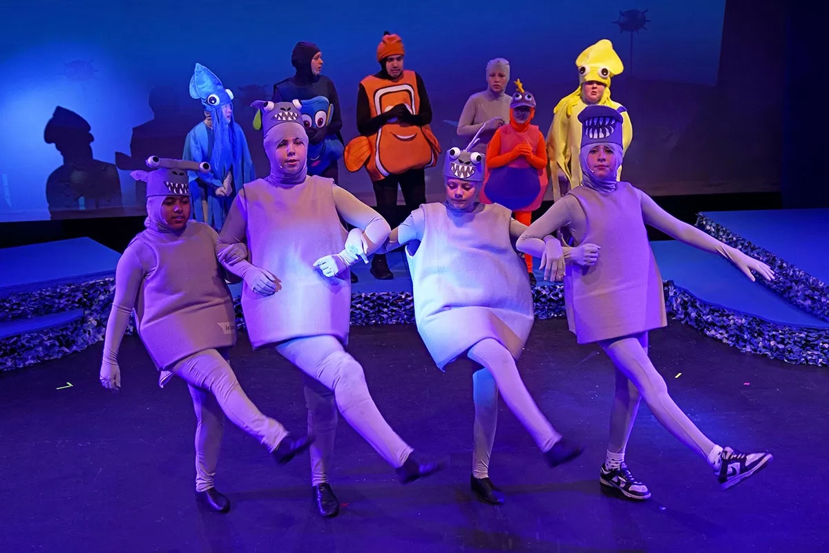 People in colorful sea creature costumes performing on stage.