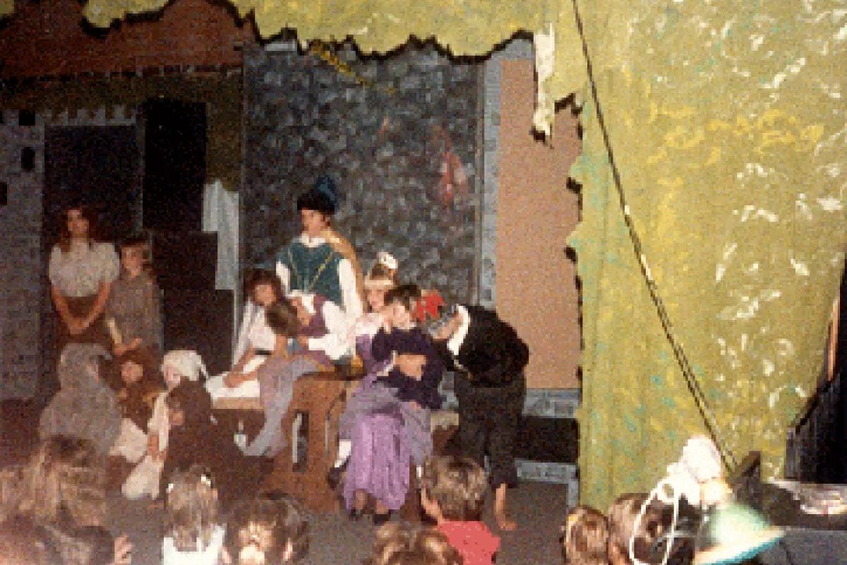 A group of children in costumes performing a play on stage.