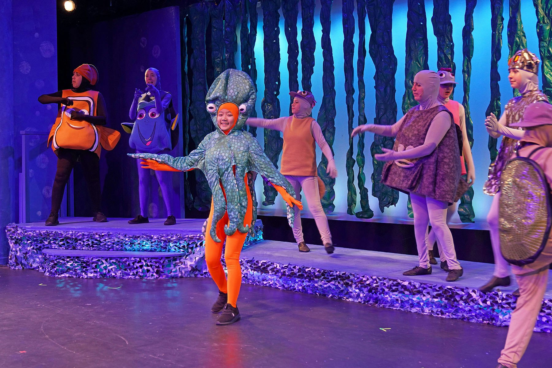 People in colorful sea creature costumes performing on stage.