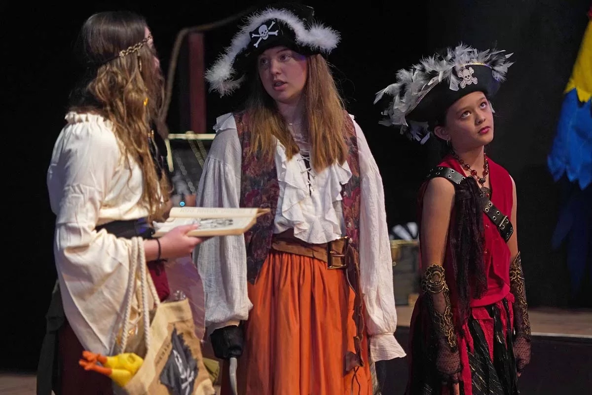 Three people in pirate costumes talking on stage.