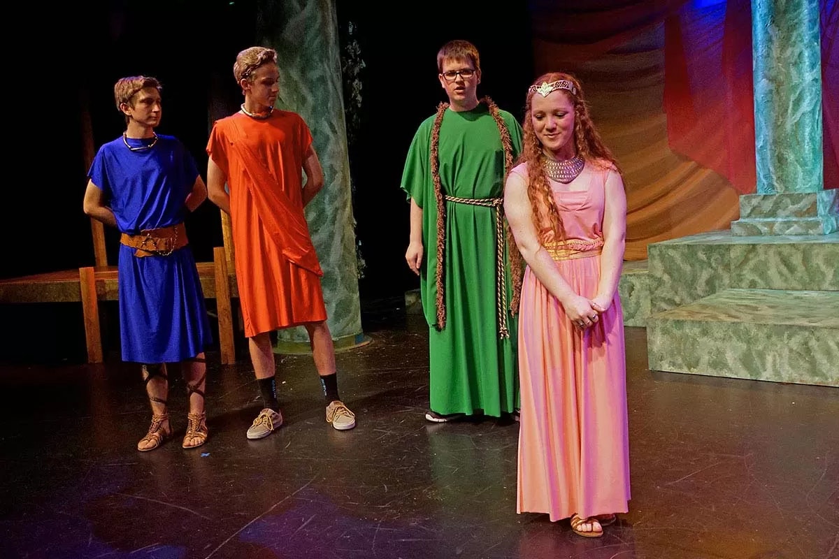 People in colorful costumes on a stage, likely performing a play.