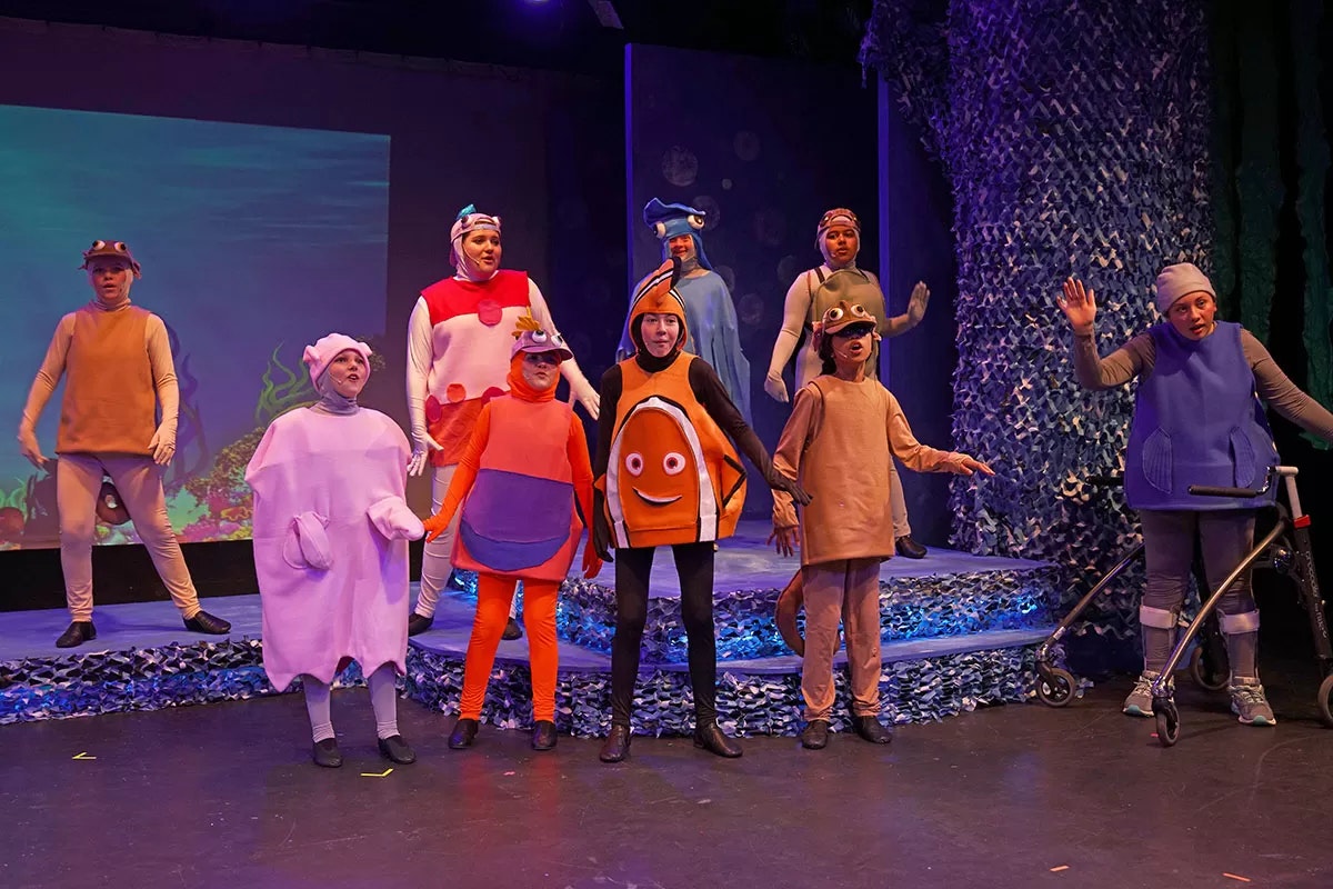 People in colorful sea creature costumes performing on stage.