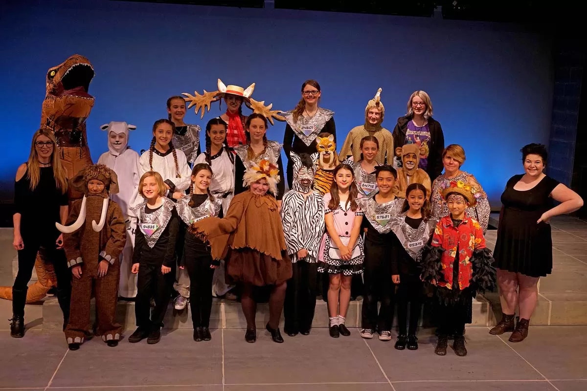 A group of people in animal and character costumes posing on stage.