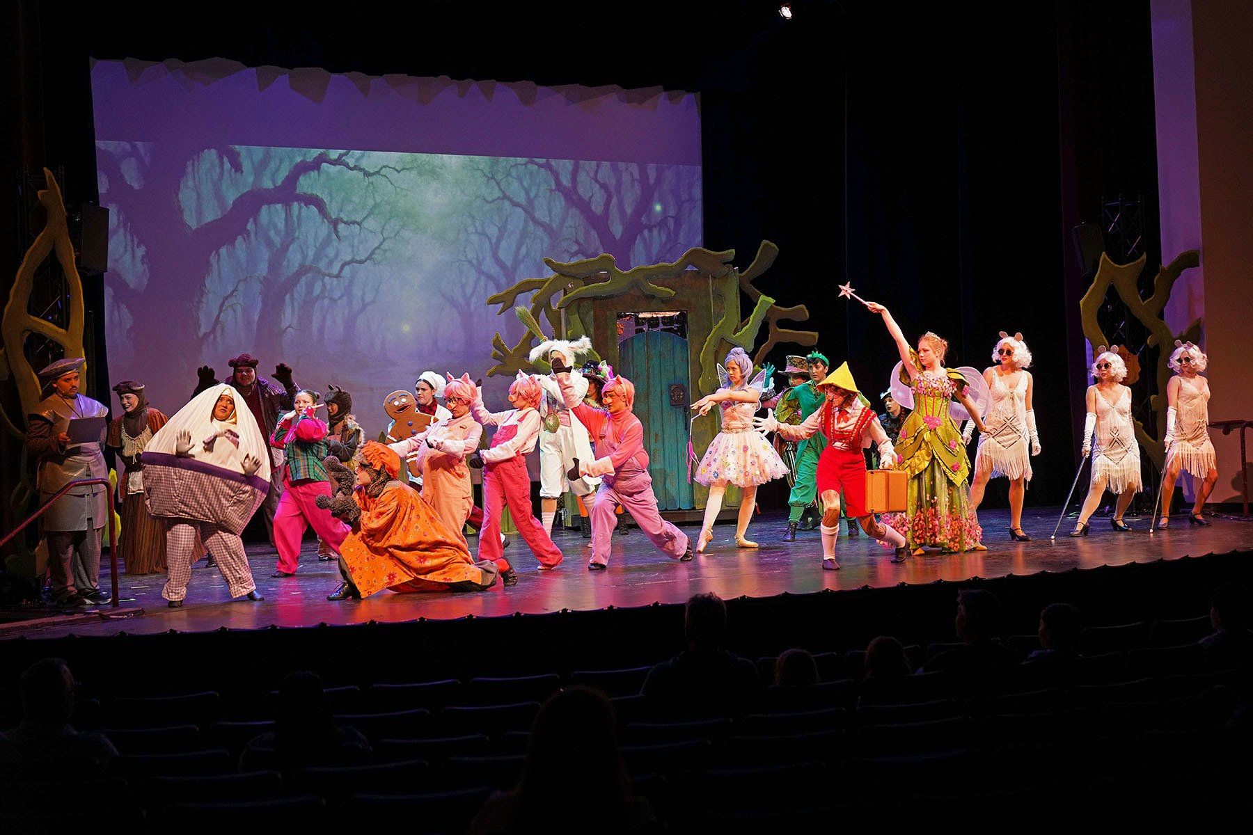 A theatrical performance with actors in colorful costumes depicting fairy tale characters on stage.