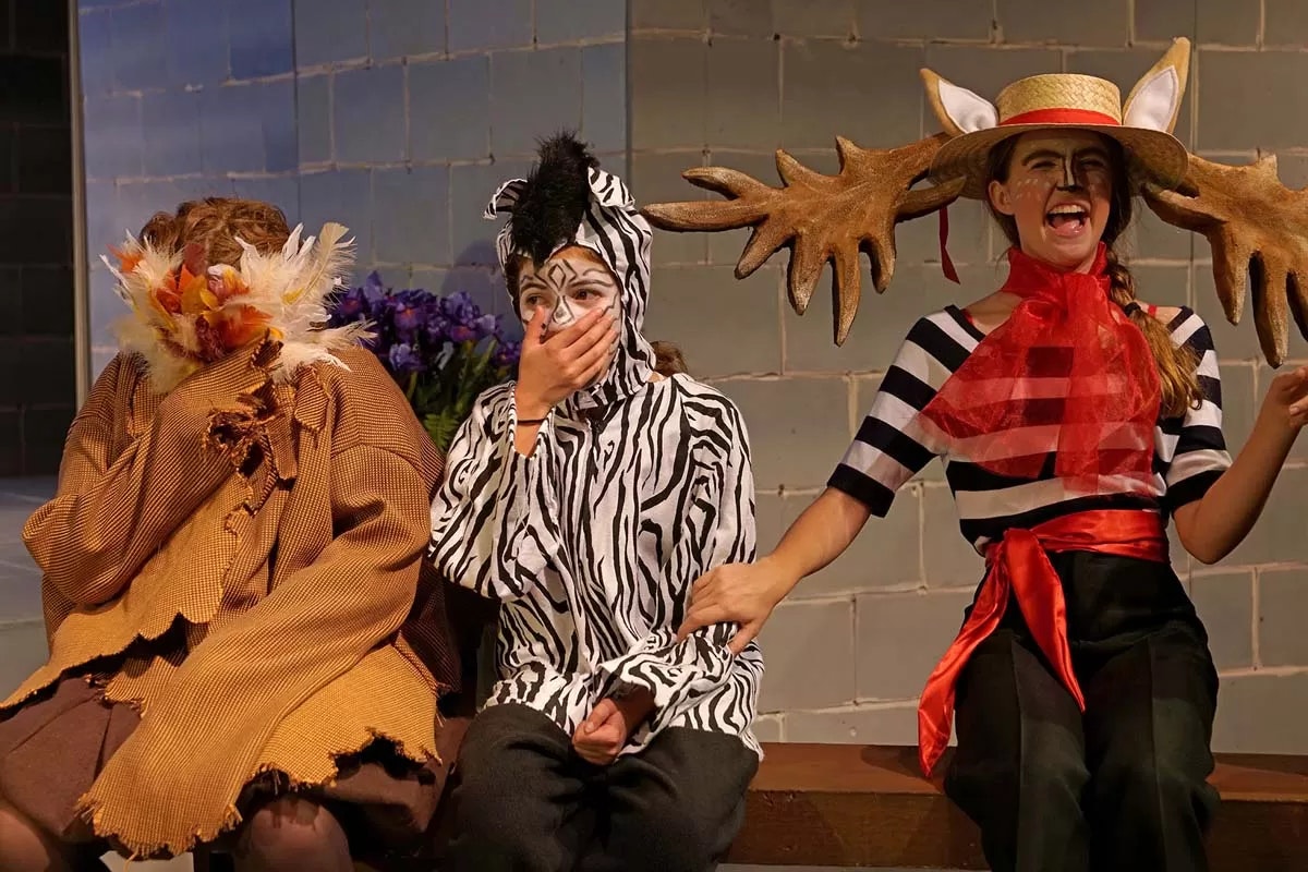Three people in animal costumes sitting together, one dressed as a bird, one as a zebra, and one as a moose, with a humorous vibe.