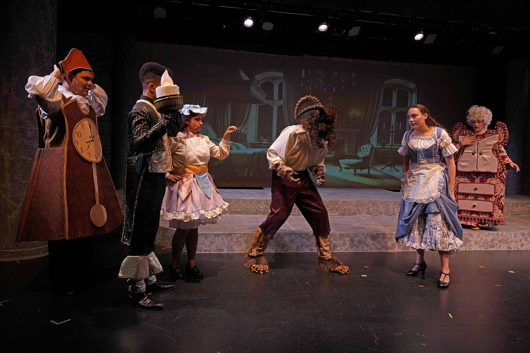 A theatrical performance with actors in costume, resembling characters from "Beauty and the Beast."