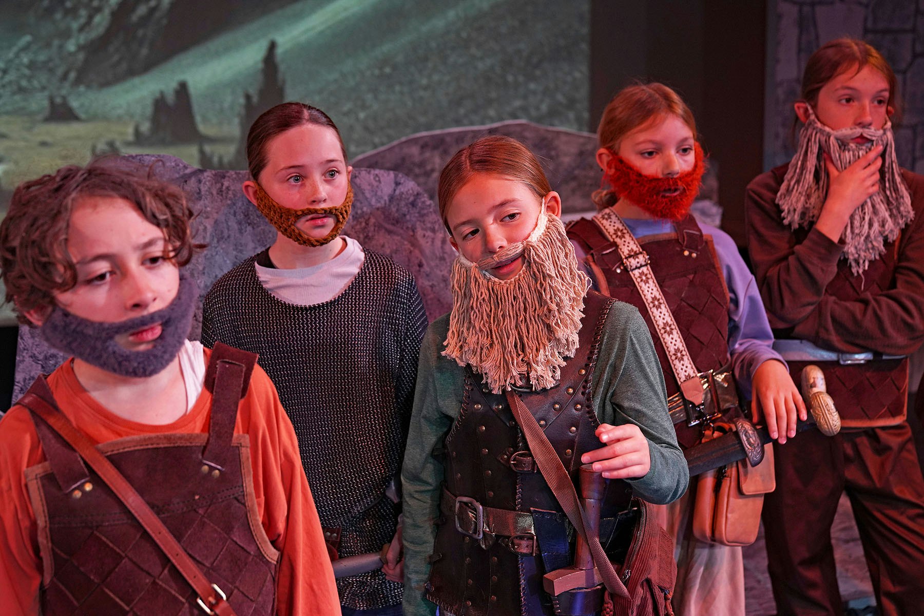 Children dressed as dwarves with fake beards and medieval costumes, standing in a fantasy setting.