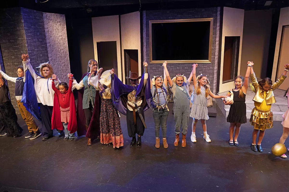 A group of children in costumes holding hands, likely after a theater performance.
