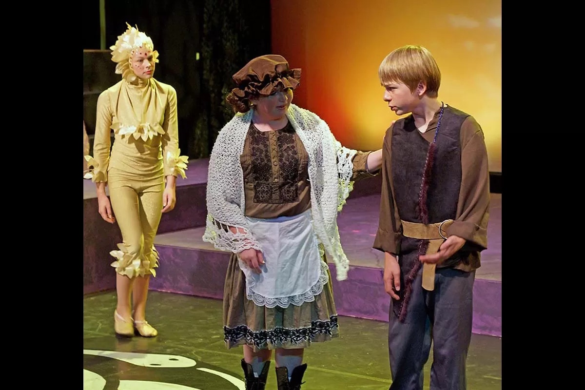 Three people on stage in theatrical costumes, engaged in performance.