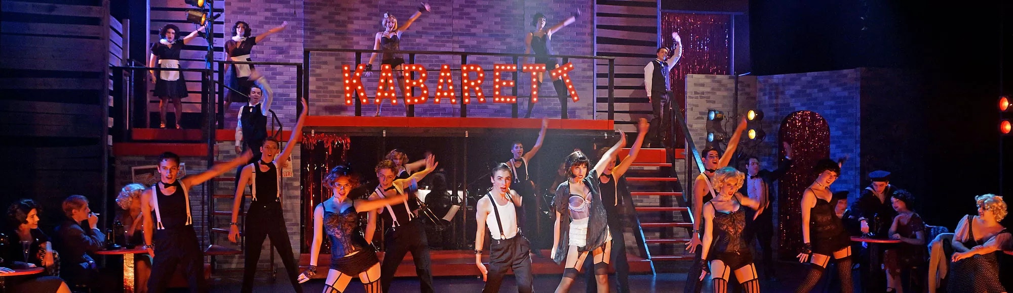 A theatrical performance with dancers in costume on stage, under a lit "KABARETT" sign.