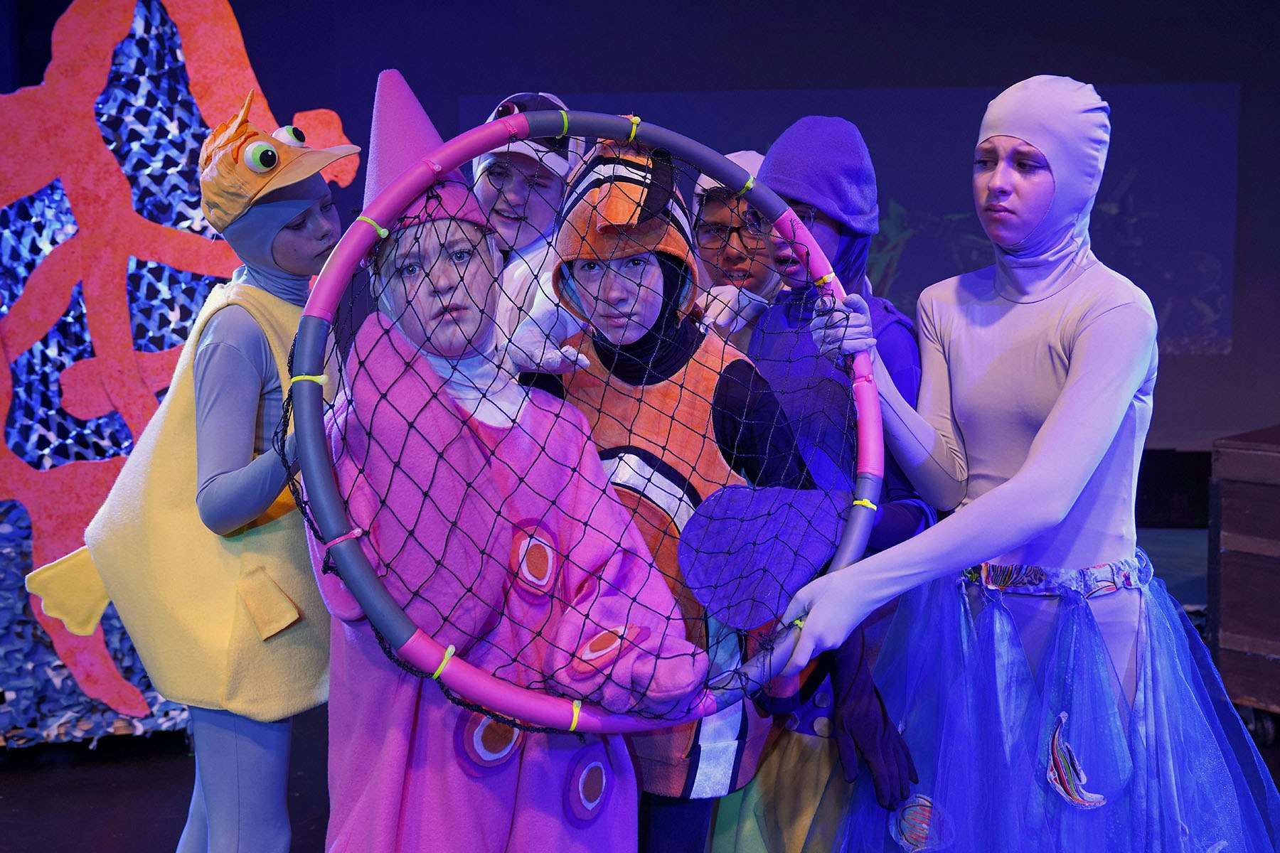 People in colorful costumes performing with a net, possibly a play or production.