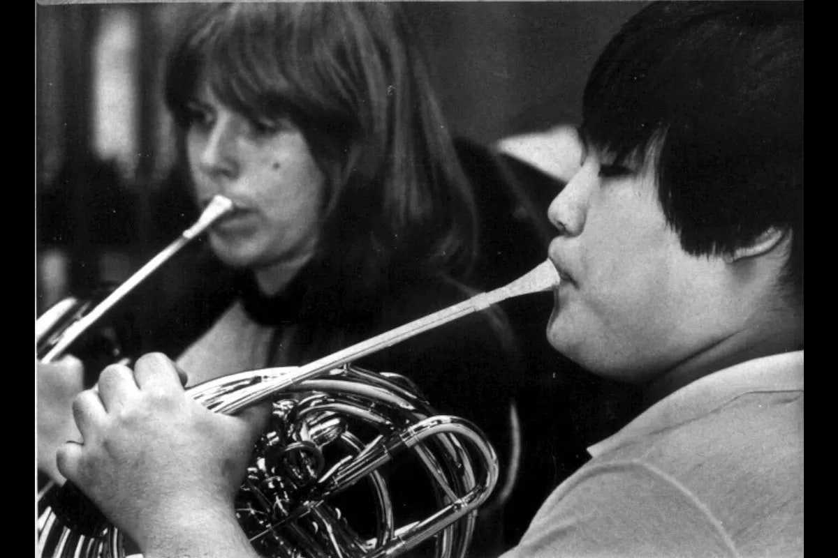 Two musicians play the French horn. Black and white photo.