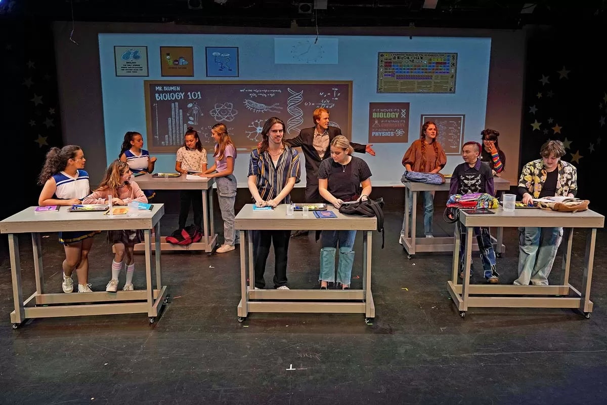Students in a classroom, set up like a play or presentation with Biology 101 on the board.