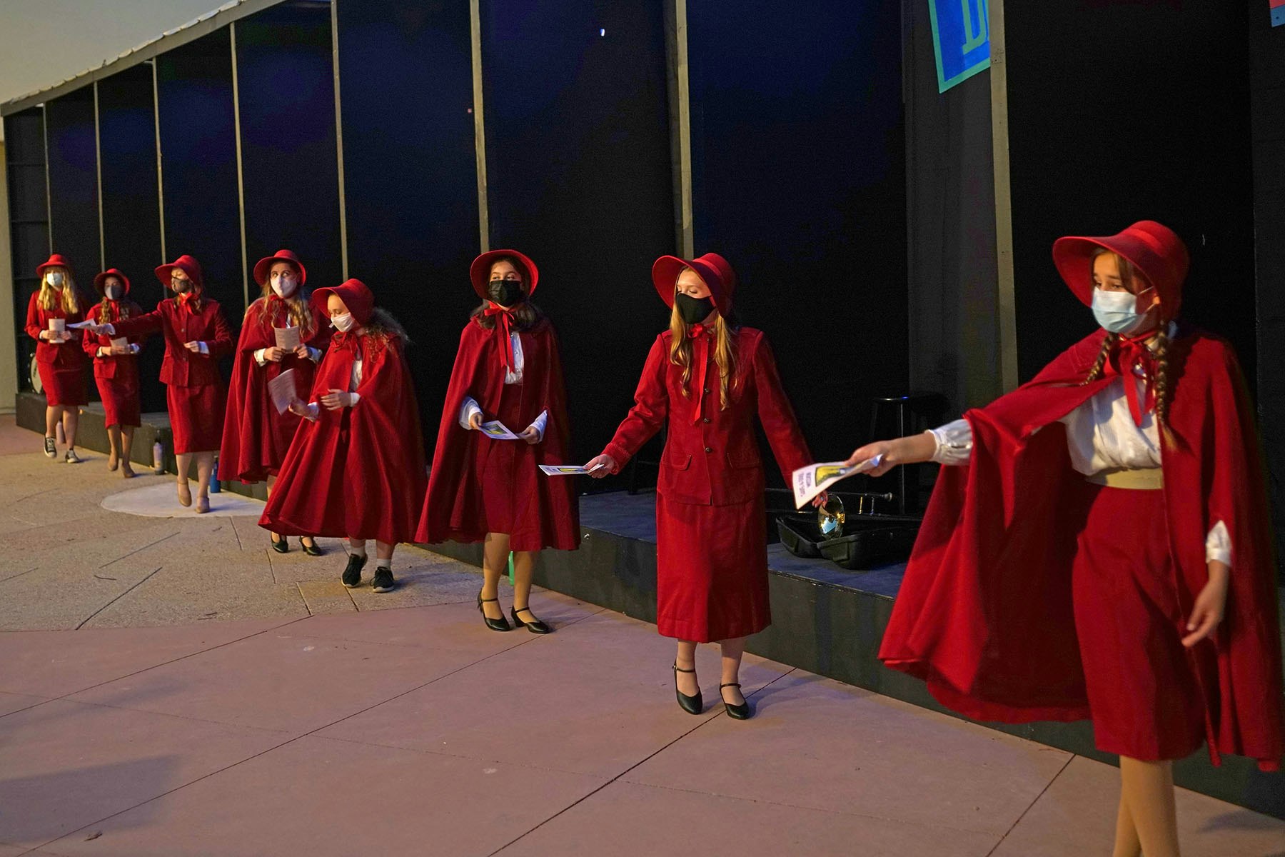 People dressed in red cloaks and hats handing out flyers.