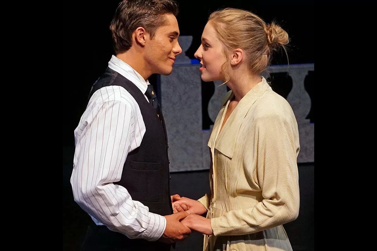 Two people in formal attire holding hands and facing each other closely.